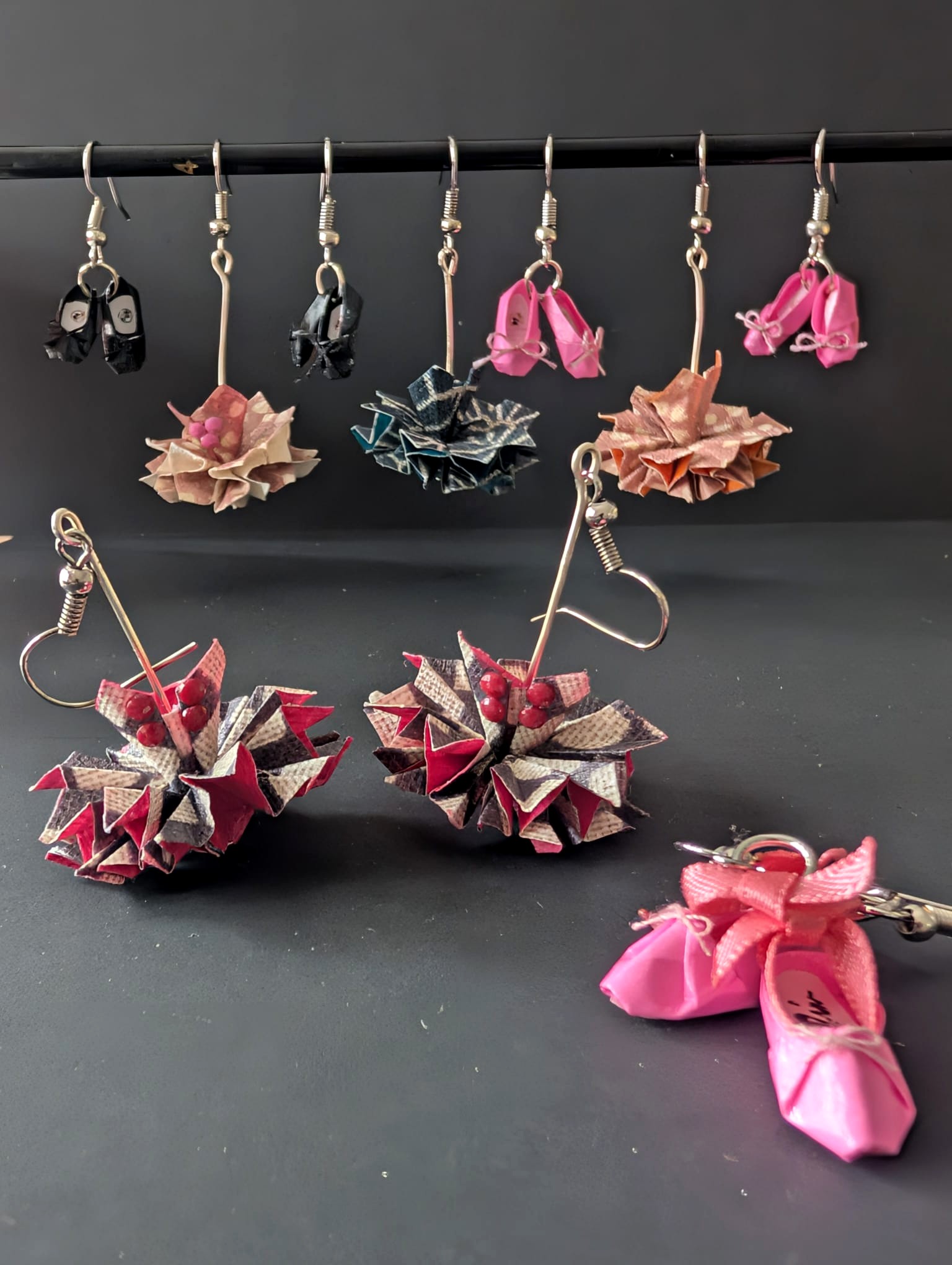 A selection of handmade origami jewellery displayed on a dark studio background